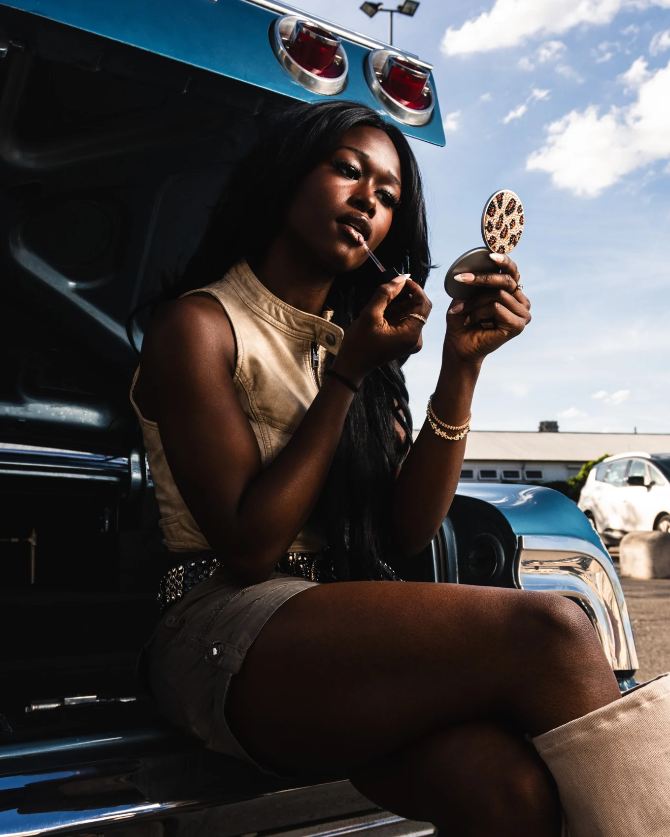 A beauty portrait with a mirror beside a vintage car.