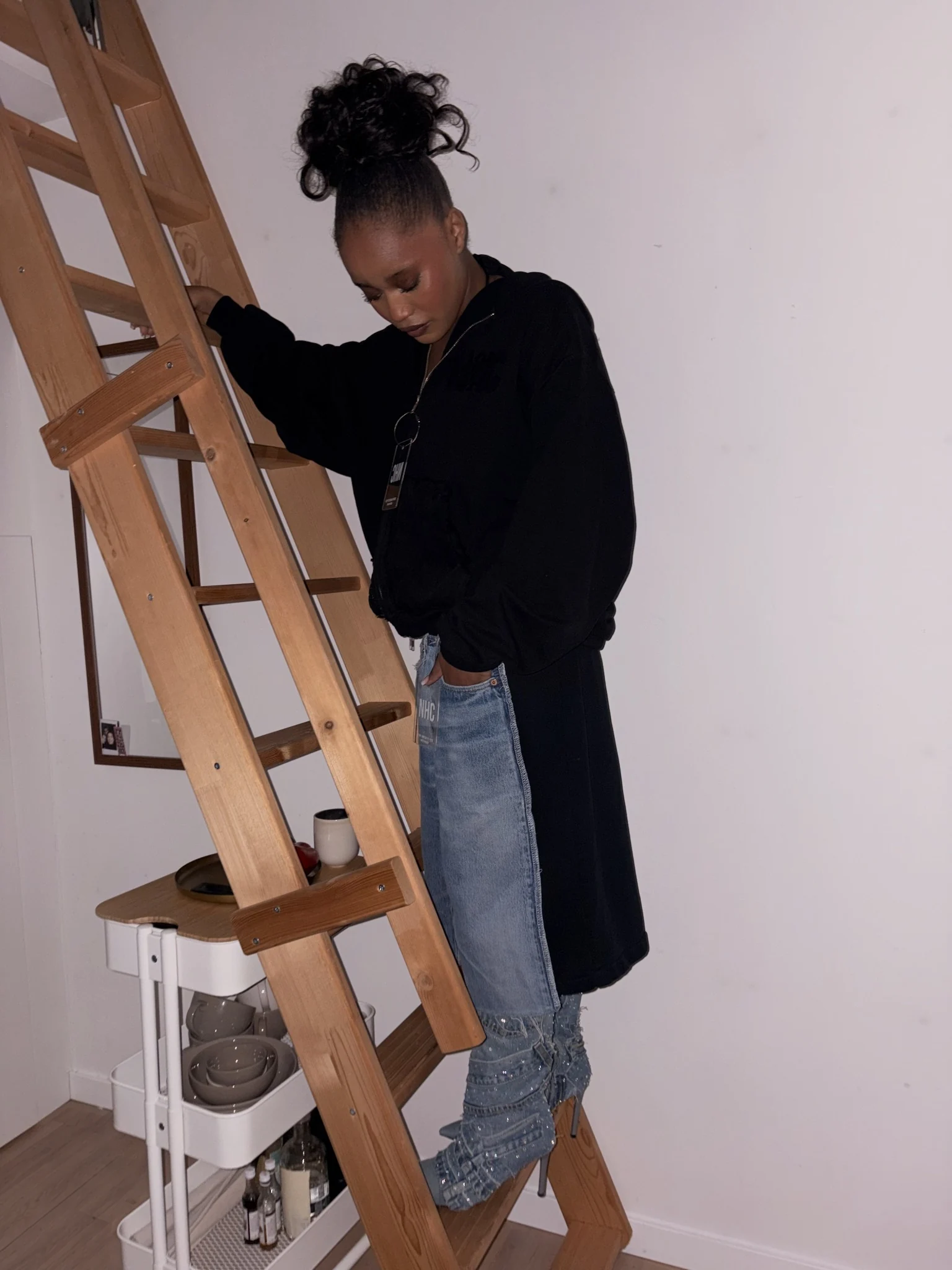 The styled denim look beside a wooden ladder.