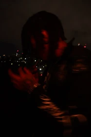 A portrait in motion under red light on the balcony.