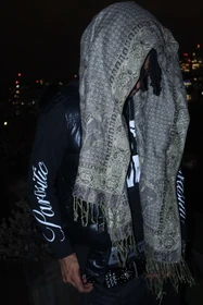 A side portrait with the patterned scarf framing the black vest.