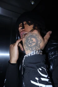 A close elevator portrait focusing on a tattooed hand and silver bracelet.