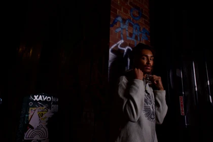 A grey hooded knit look beside a dark graffiti-covered doorway.