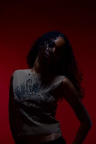 A close view of a sleeveless illustrated knit top against the red backdrop.
